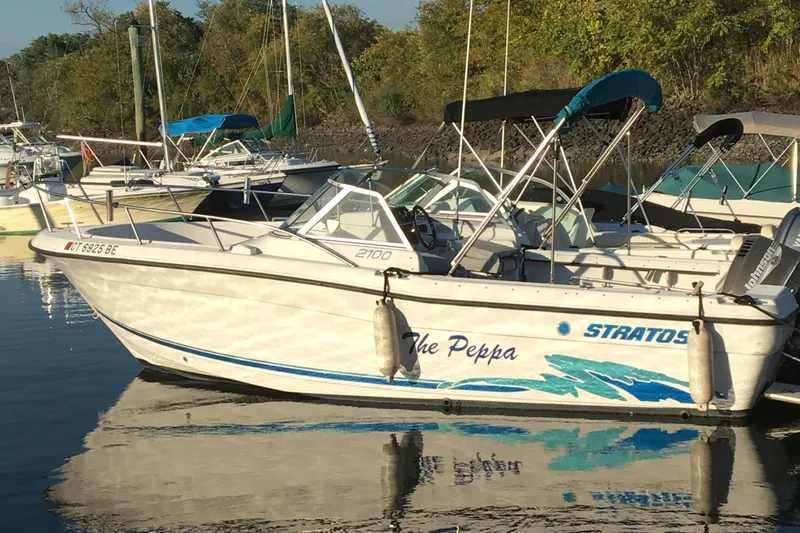 Slide: The Image of 1998 Stratos 2100 boat docked in a marina with other boats. - 9