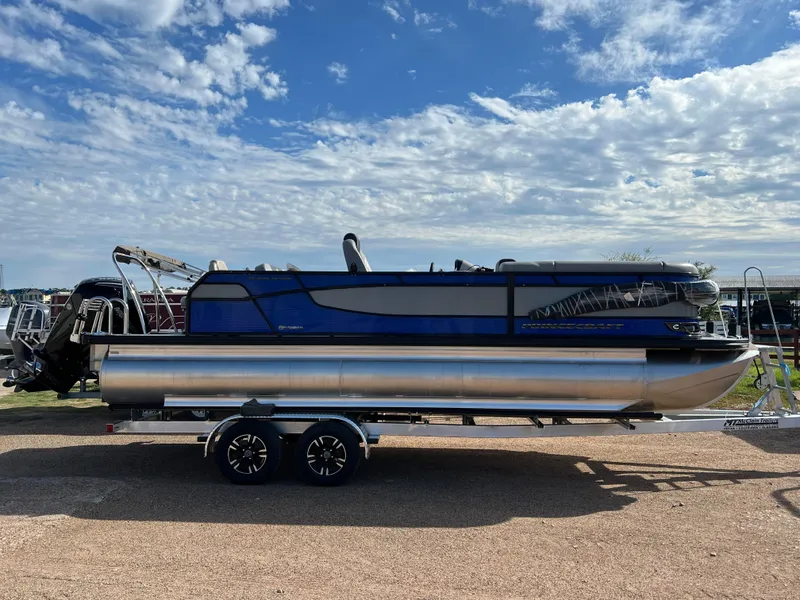 Slide: The Image of 2024 Princecraft Quorum 23 RL pontoon boat on a trailer under a blue sky. - 1
