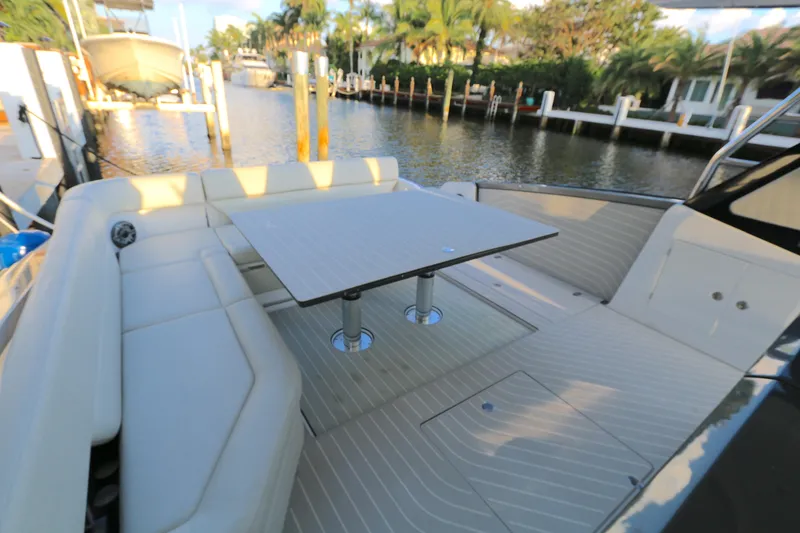 Slide: The Image of 2022 Azimut 47 VERVE yacht with elegant seating and table on deck, docked by a serene waterfront. - 13