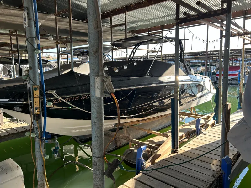 Slide: The Image of 2017 Scarab 255 boat docked in a marina, partially covered, with string lights above. - 2