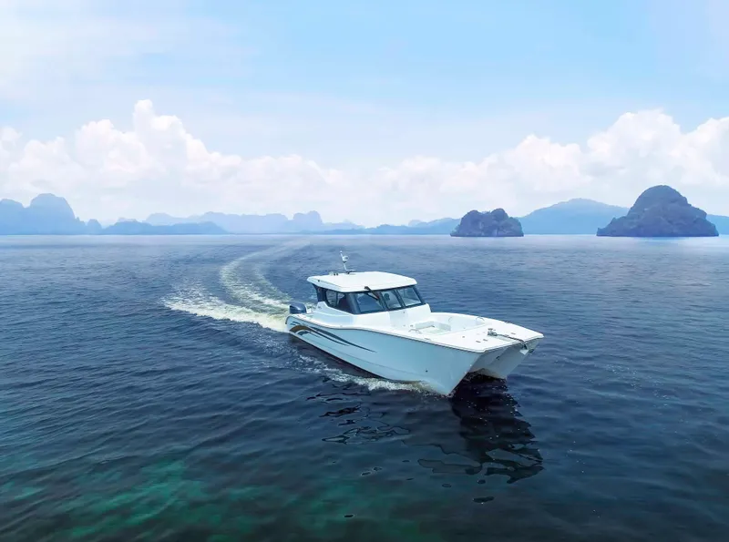 Slide: The Image of Custom SILVERCAT 34HT 2025 cruising on clear blue ocean with scenic island backdrop. - 5