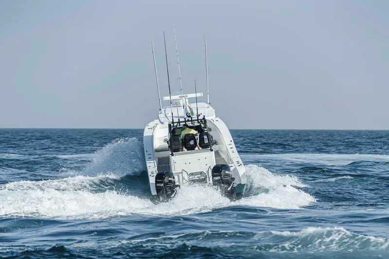 Slide: The Image of 2025 SilverCAT 34 CC boat navigating ocean waves, rear view, with fishing rods visible. - 14