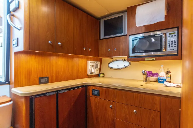 Slide: The Image of 2004 Tiara Yachts 38 Express kitchen with wooden cabinets, microwave, and countertop appliances. - 17