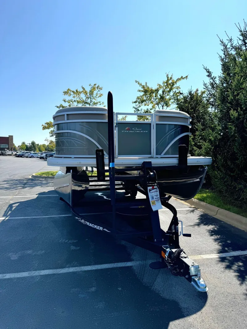 Slide: The Image of 2024 Sun Tracker Party Barge 24 DLX pontoon boat on trailer in parking lot. - 2
