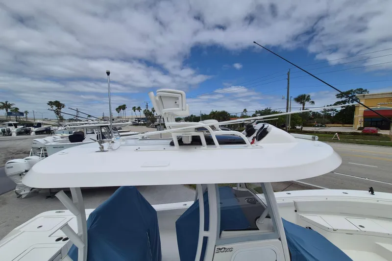 Slide: The Image of 2024 Regulator 30XO boat with T-top and fishing equipment, parked outdoors under cloudy sky. - 11