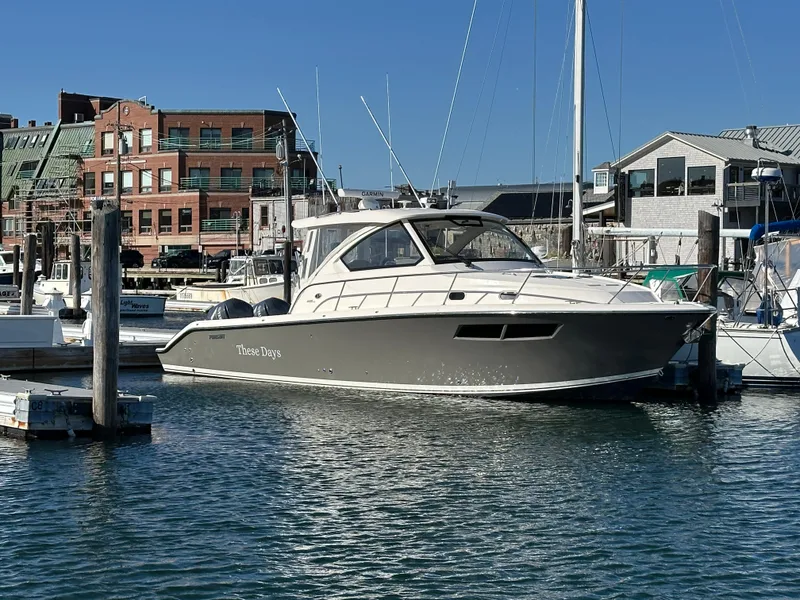 Slide: The Image of 2017 Pursuit OS 355 boat docked in a marina with buildings in the background. - 0