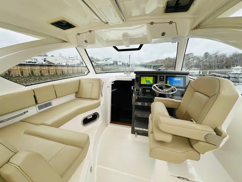 Slide: The Image of Interior of a 2017 Pursuit OS 355 boat with beige seating and navigation equipment. - 13