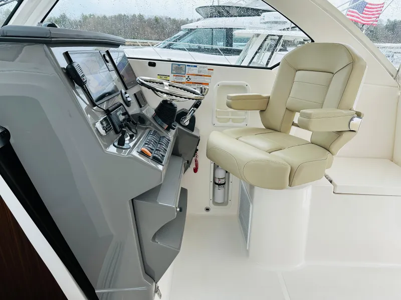 Slide: The Image of Helm station of a 2017 Pursuit OS 355 boat with beige captain's chair. - 18