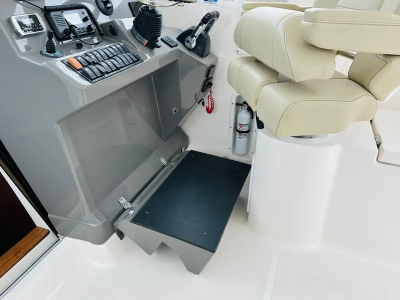Slide: The Image of 2017 Pursuit OS 355 helm station with beige captain's chair and control panel. - 19