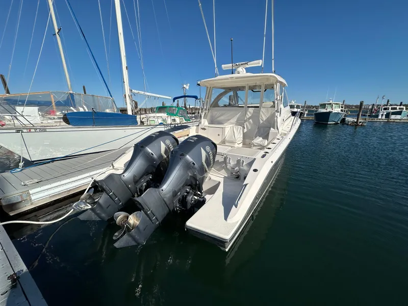 Slide: The Image of 2017 Pursuit OS 355 boat docked with dual outboard engines in a marina. - 2