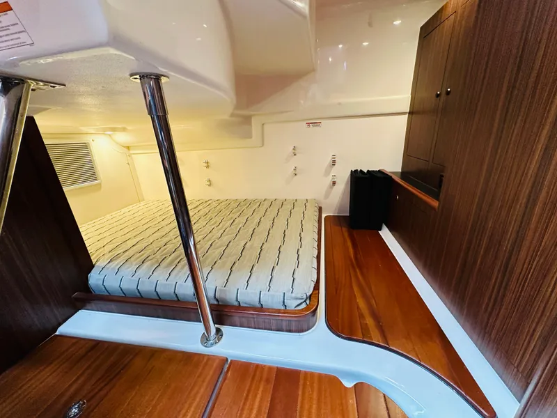 Slide: The Image of 2017 Pursuit OS 355 cabin interior with bed and wooden cabinetry. - 36