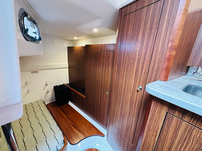 Slide: The Image of 2017 Pursuit OS 355 cabin interior with wood paneling and compact kitchenette. - 37