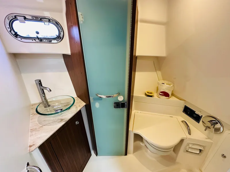 Slide: The Image of 2017 Pursuit OS 355 boat bathroom with glass sink, toilet, and frosted door. - 39