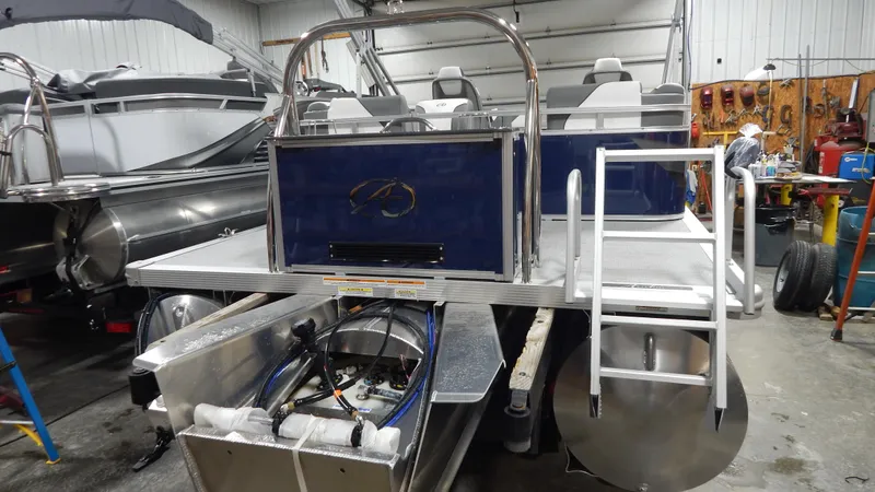 Slide: The Image of 2024 Avalon Venture Quad Lounge Tritoon in a workshop, rear view with ladder and seating. - 4