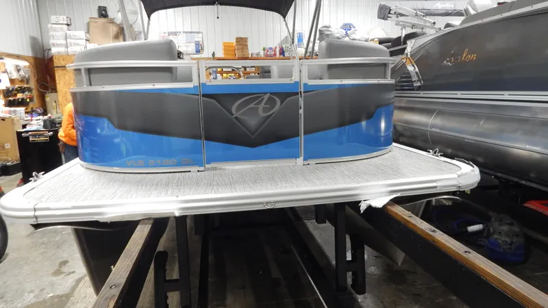 Slide: The Image of 2024 Avalon VLS Quad Lounge 21' pontoon boat in a showroom. - 2