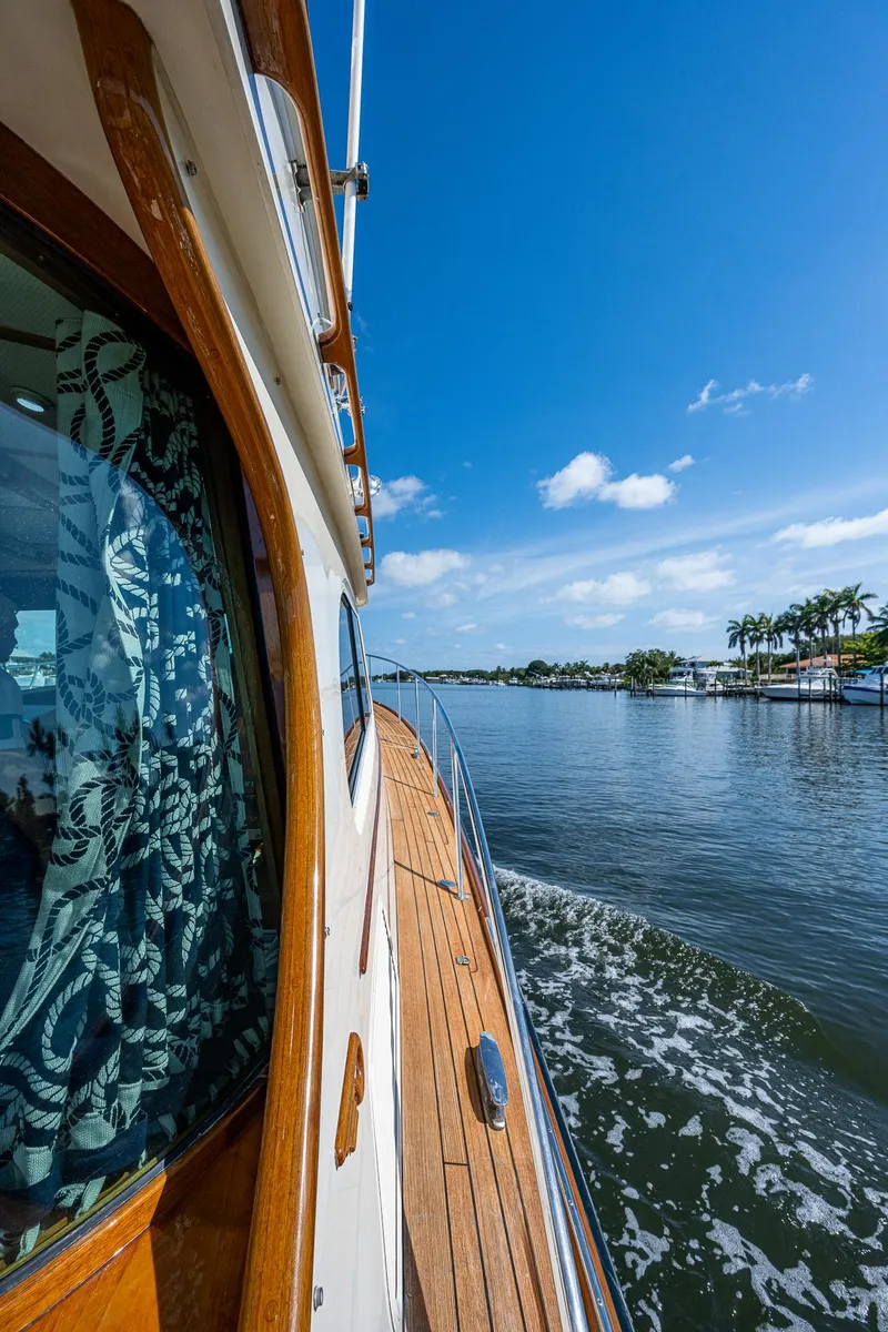 Slide: The Image of 2008 Hinckley Talaria 44 FB cruising on a sunny day, showcasing elegant design and scenic waterway. - 33