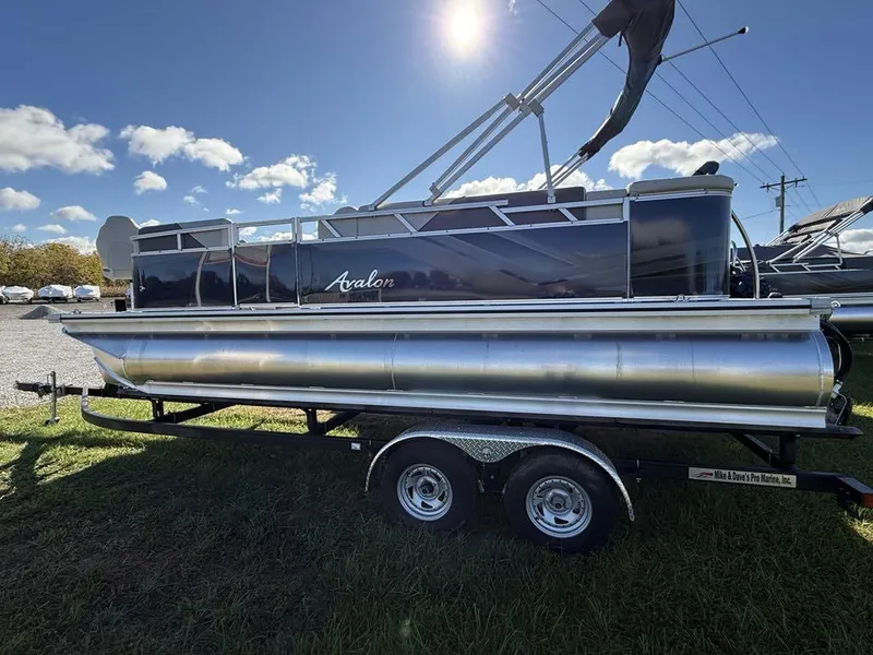 Slide: The Image of 2024 Avalon Venture Cruise Bow Fish pontoon boat on trailer under sunny sky. - 2