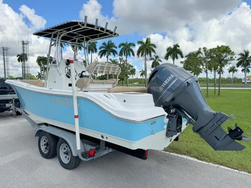 Slide: The Image of 2021 NauticStar 2302 Legacy boat on trailer, blue and white, with Yamaha outboard motor. - 2