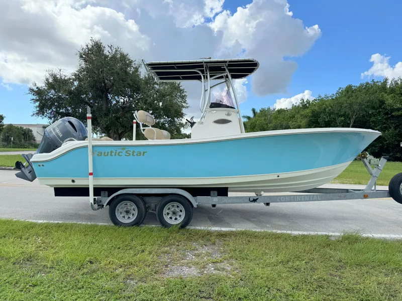 Slide: The Image of 2021 NauticStar 2302 Legacy boat on trailer, light blue hull, parked outdoors. - 5