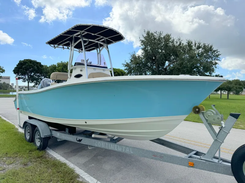 Slide: The Image of 2021 NauticStar 2302 Legacy boat on trailer, light blue hull, parked outdoors. - 6