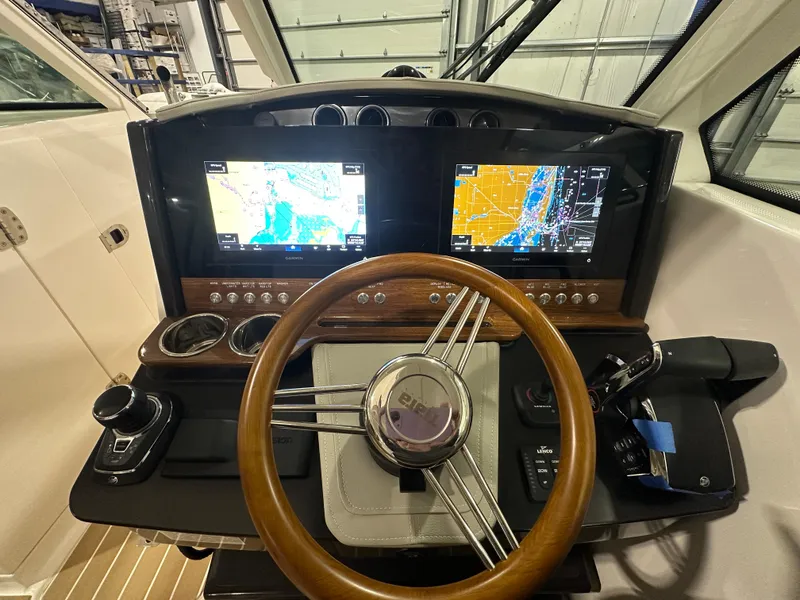 Slide: The Image of 2024 Tiara Yachts 34 LX helm with dual navigation screens and wooden steering wheel. - 20