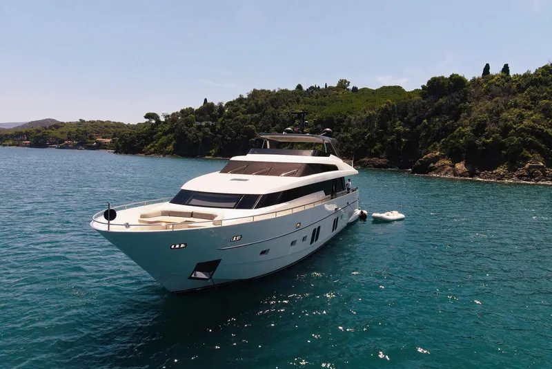 Slide: The Image of 2016 Sanlorenzo SL96 yacht anchored in a serene bay with lush greenery. - 2