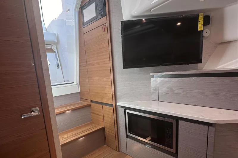 Slide: The Image of Interior of 2024 Tiara Yachts 48 LS with TV, microwave, and wooden stairs. - 33