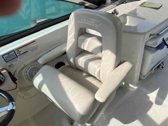 Slide: The Image of 2018 Boston Whaler 270 Vantage captain's chair with armrests and white upholstery. - 25