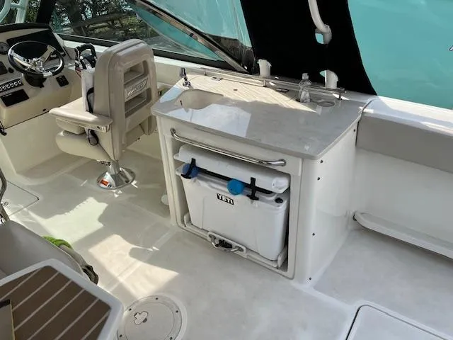 Slide: The Image of 2018 Boston Whaler 270 Vantage boat interior with helm, sink, and cooler. - 37
