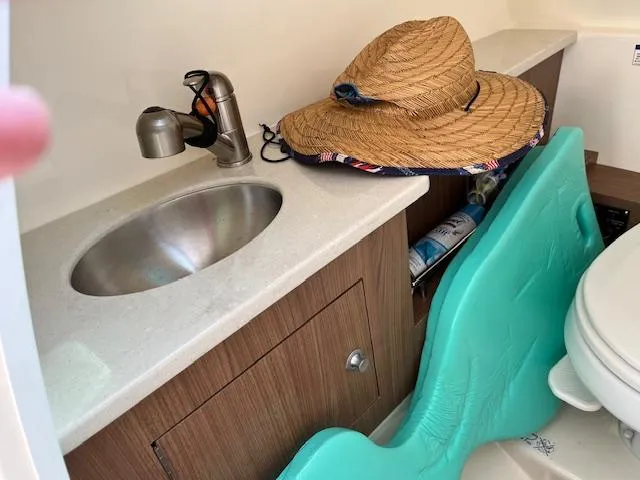 Slide: The Image of 2018 Boston Whaler 270 Vantage bathroom sink and storage area with straw hat. - 47