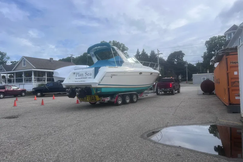 Slide: The Image of 1997 Formula 34 PC boat on trailer, labeled "Plan Sea," in parking lot with orange container. - 32