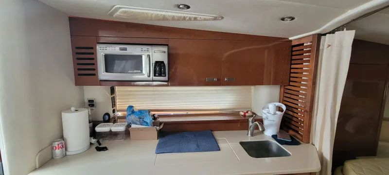 Slide: The Image of 2008 Sea Ray 350 Sundancer kitchen with microwave, sink, and storage cabinets. - 23