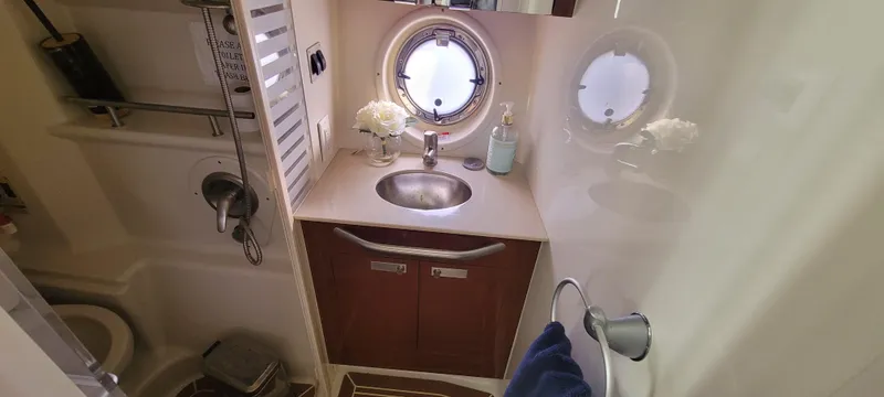 Slide: The Image of 2008 Sea Ray 350 Sundancer bathroom with sink, porthole, and storage cabinets. - 27