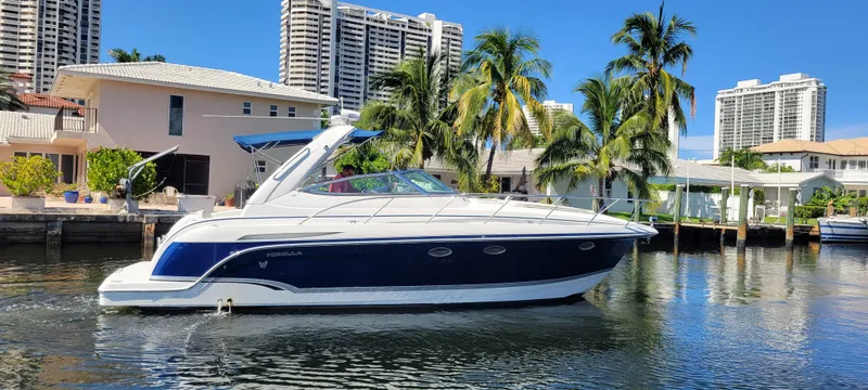 The Image of 2006 Formula 34 PC yacht cruising on a sunny waterfront with palm trees and buildings. - 0
