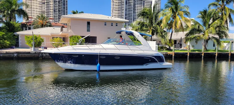 Slide: The Image of 2006 Formula 34 PC yacht cruising on a sunny waterfront with palm trees and buildings. - 1