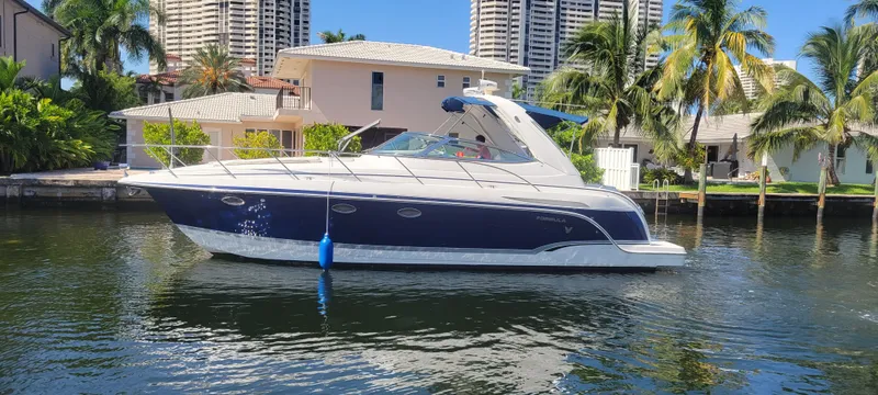 Slide: The Image of 2006 Formula 34 PC yacht on a sunny waterfront with palm trees and buildings. - 12