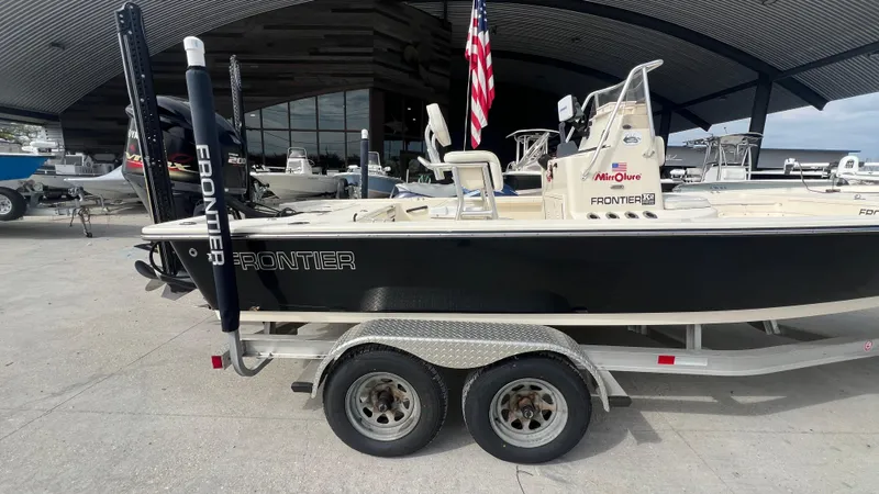 Slide: The Image of 2012 Frontier 2104 boat on a dual-axle trailer, docked at a marina. - 3