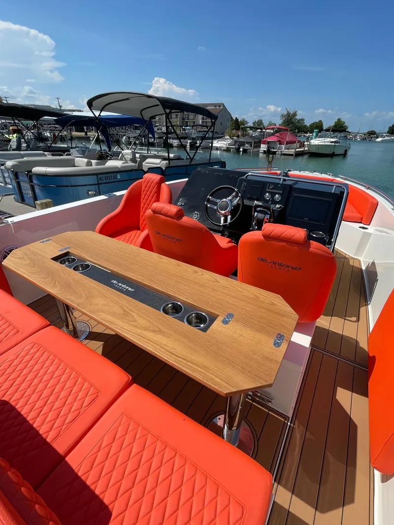 Slide: The Image of 2020 De Antonio Yachts D 28 with orange seating and wooden table docked at marina. - 17