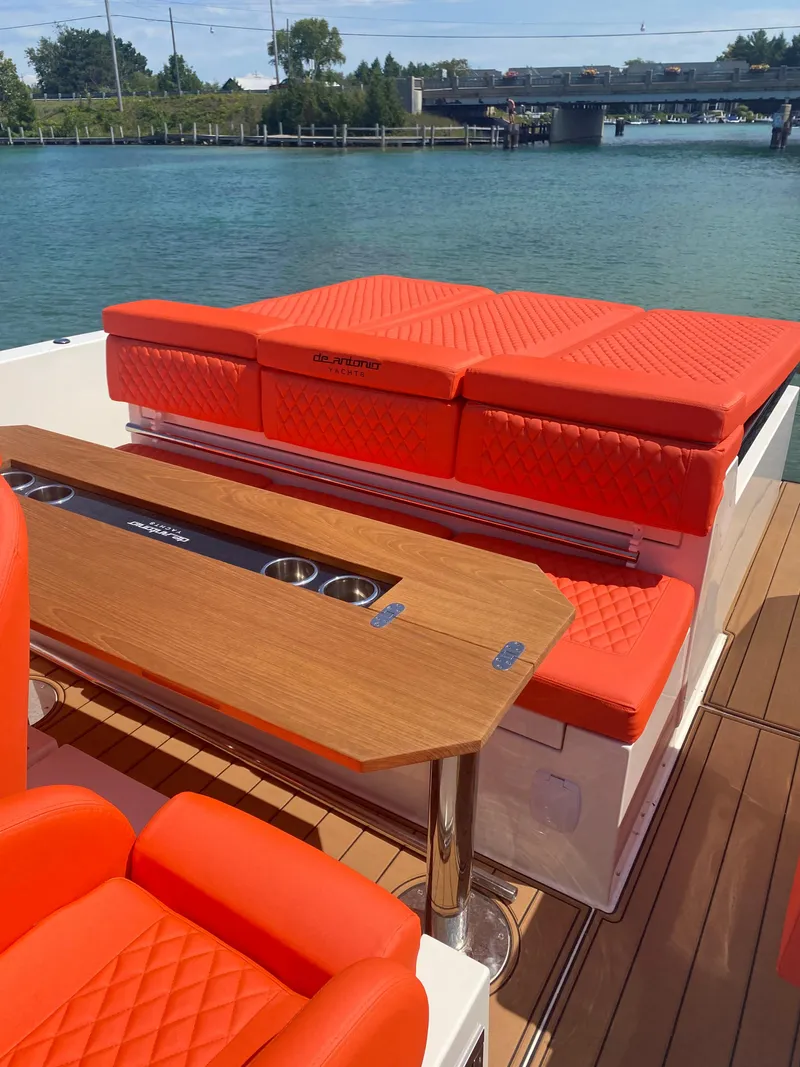Slide: The Image of 2020 De Antonio Yachts D 28 with red seating and wooden table on deck. - 25