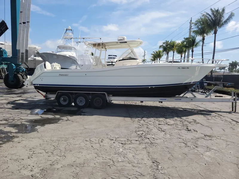 Slide: The Image of 2002 Pursuit 3070 Center Console boat on a trailer in a marina. - 0