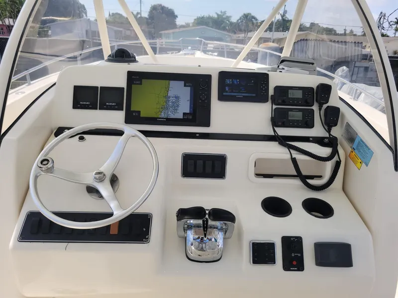 Slide: The Image of 2002 Pursuit 3070 Center Console boat dashboard with steering wheel, navigation screens, and controls. - 3