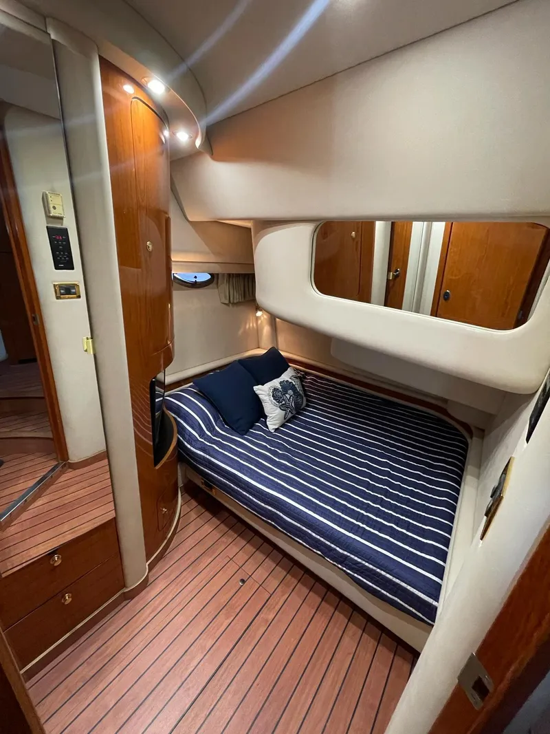 Slide: The Image of 2000 Sea Ray 450 Express Bridge cabin with striped bedding and wooden interior. - 14