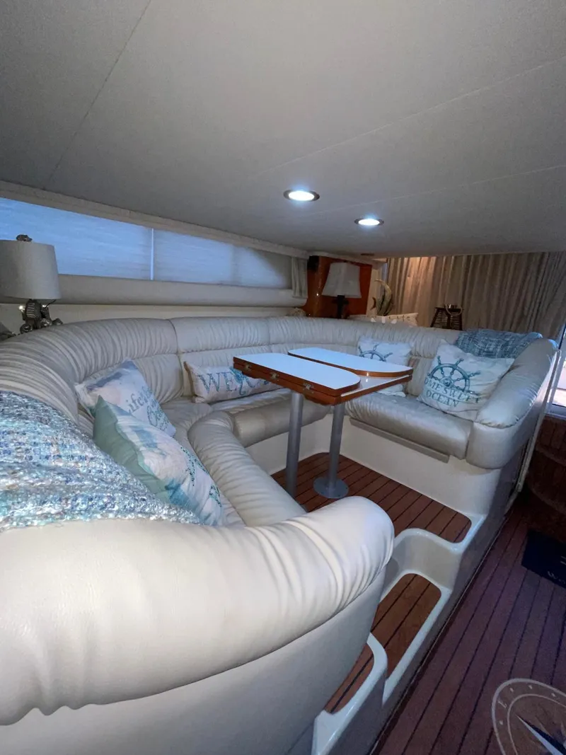 Slide: The Image of Interior of 2000 Sea Ray 450 Express Bridge with plush seating and wooden table. - 16