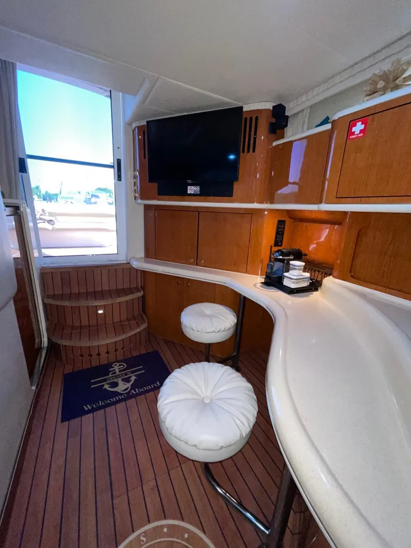 Slide: The Image of Interior of 2000 Sea Ray 450 Express Bridge with TV, bar stools, and wooden cabinetry. - 18