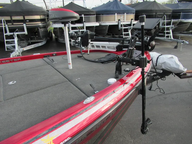 Slide: The Image of 2016 Skeeter FX 21 bass boat with red exterior, docked near other boats. - 2