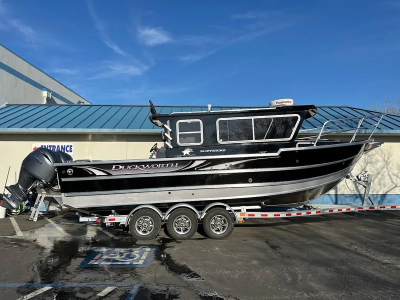 Slide: The Image of 2024 Duckworth 26 Offshore boat on trailer, parked outside a building. - 1