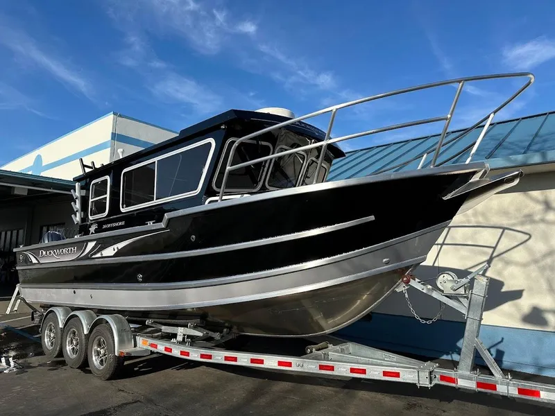 Slide: The Image of 2024 Duckworth 26 Offshore boat on a trailer, black and silver design, parked outdoors. - 2