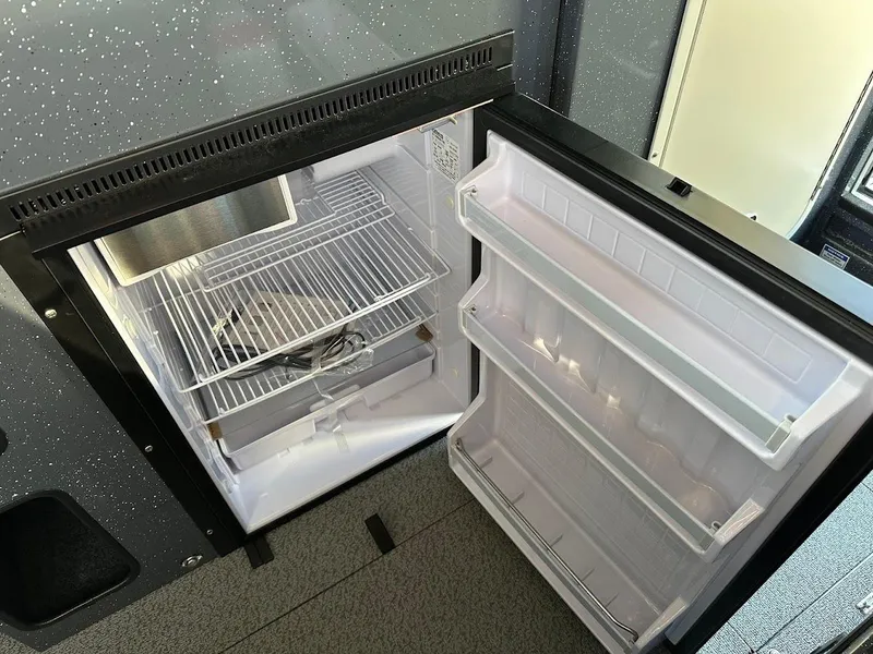 Slide: The Image of Open refrigerator inside 2024 Duckworth 26 Offshore boat, showing empty shelves and door compartments. - 49