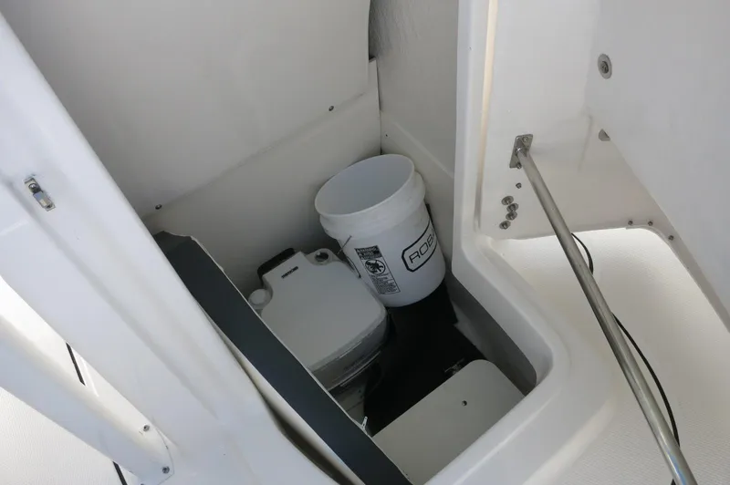 Slide: The Image of 2024 Robalo 222 Explorer CC storage compartment with bucket and portable toilet. - 19