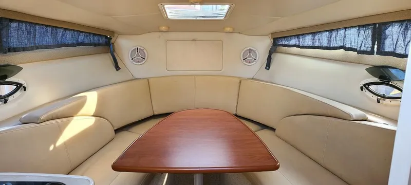 Slide: The Image of Interior of 2005 Bayliner 265 boat with beige seating and wooden table. - 7